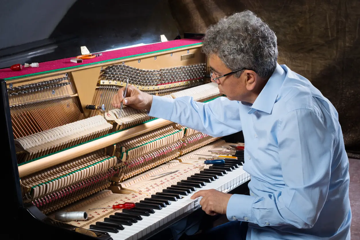 Instrument technician tuning a piano.